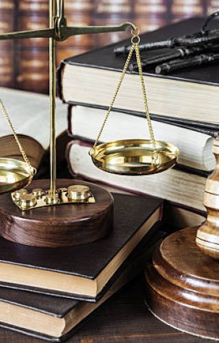 Wood gavel, bunch of keys, scales and stack of old books against the background of a row of antique books bound in leather